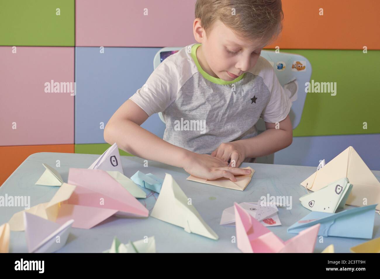 6 anni ragazzo fa un origami aerei e rane durante la quarantena Covid-19 Foto Stock