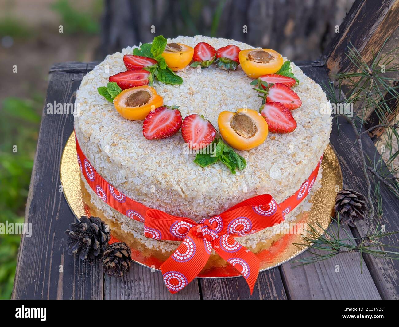Torta a strati fatta in casa Napoleone decorato con fragole e metà di albicocca su sfondo rustico di legno. Foto Stock