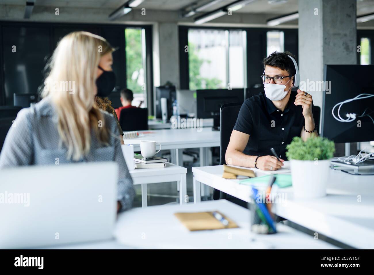 Giovani con maschere di fronte al lavoro o a scuola in ufficio dopo il blocco. Foto Stock