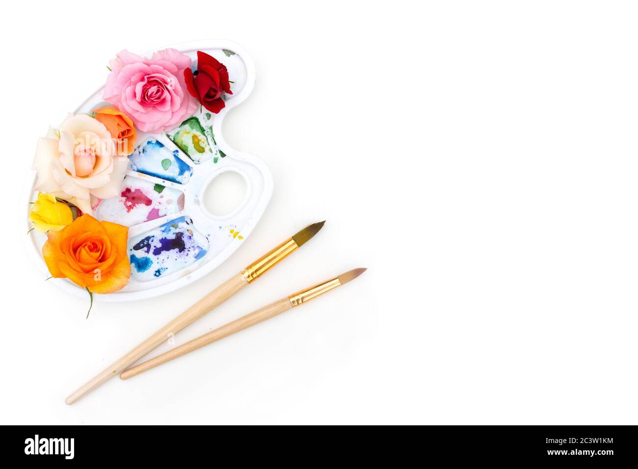 Tavolozza di colori acquerelli con boccioli di rosa multicolore e pennello artistico su sfondo bianco. I colori dell'estate. Concetto creativo di estate colorata. Foto Stock