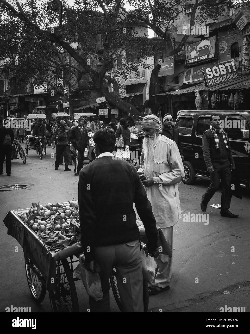 Delhi, India - l'uomo vecchio che compra frutta sul mercato di strada in Paharganj, enclave dello zaino in spalla vivace piena di pensioni di bilancio e negozi minuscoli. Foto Stock