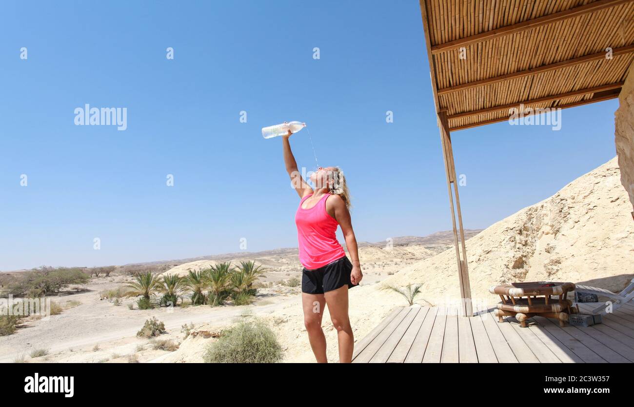 Donna si rinfresca con acqua dopo un allenamento nel deserto. Modello rilasciato Foto Stock