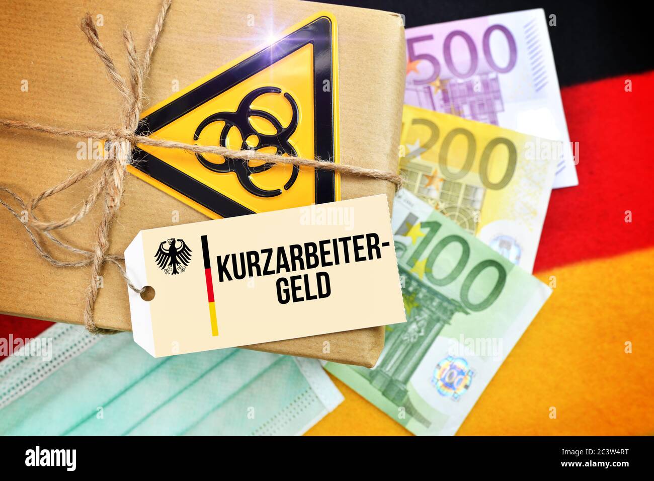 FOTOMONTAGGIO, pacchetto Biogefährdungszeichen sulla bandiera tedesca con tag e l'etichetta Kurzarbeitergeld, FOTOMONTAGE, Paket mit Biogefährdungszeichen auf Foto Stock