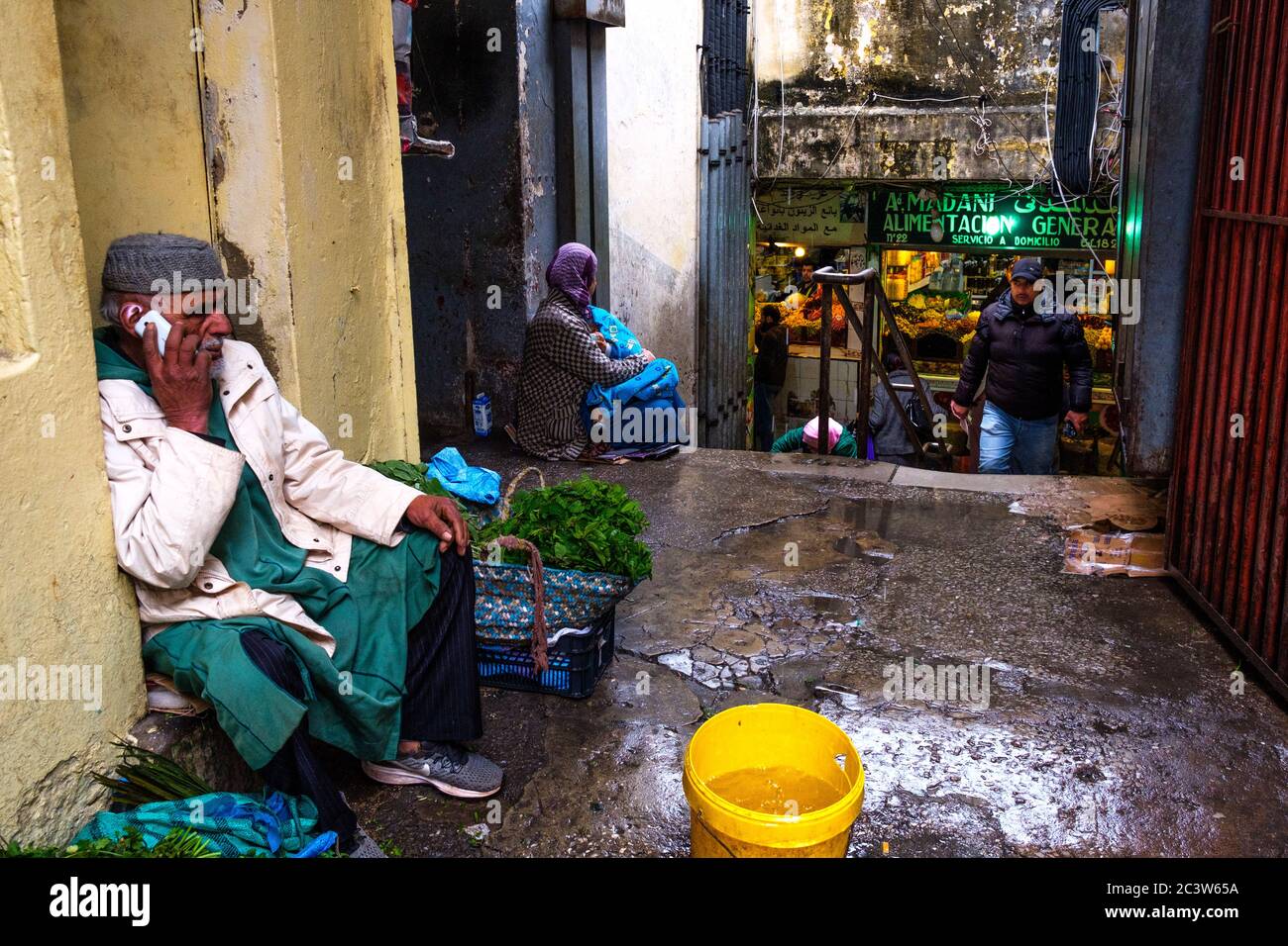 Marocco, Tetouan: Atmosfera in una strada della Città Vecchia. Peddler in una strada con il suo smartphone. La medina di Tetouan è registrata come un WOR UNESCO Foto Stock