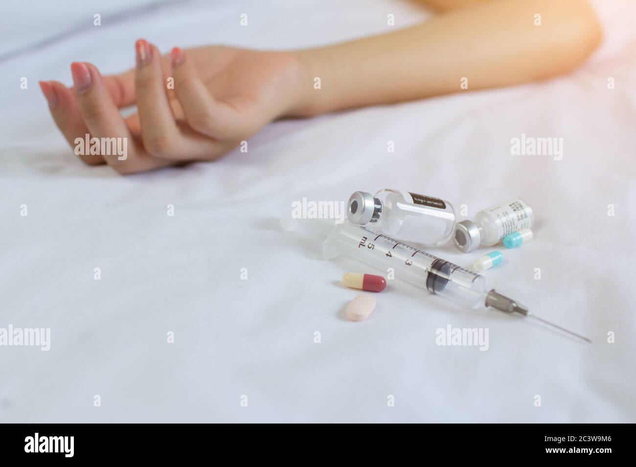 Concetto di droga - la donna è tossicodipendente per iniettare la mano passiva a letto. Pillole e iniezione Foto Stock