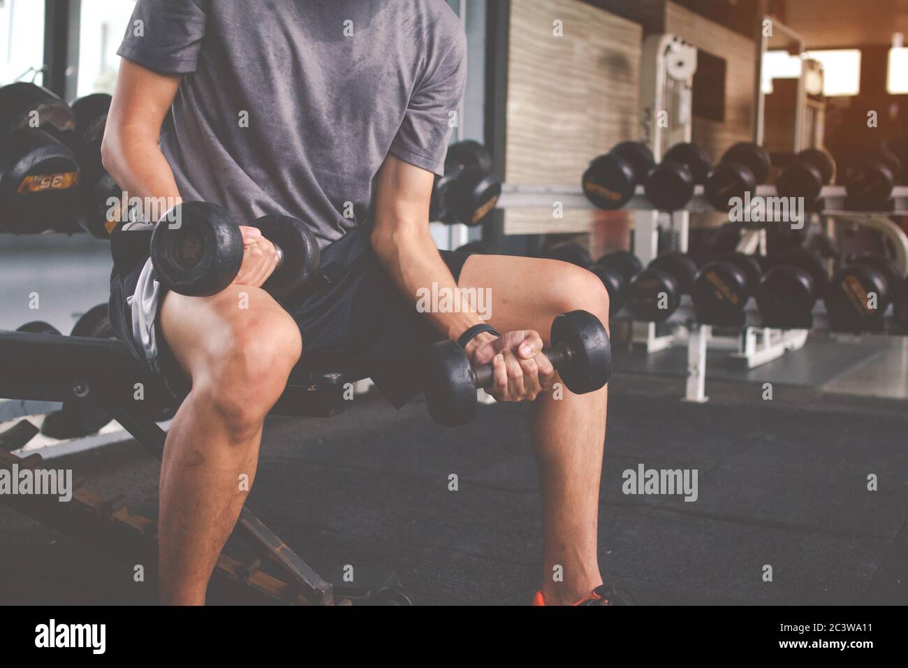 Closeup di un uomo sottile che fa esercizi con dumbbell. Fitness corpo muscolare. Concetto di fitness Foto Stock