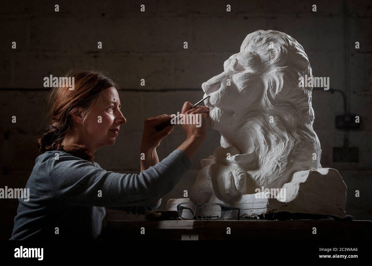Carver Kibby Schaefer lavora su un modello in gesso di Aslan, un personaggio della serie di libri per bambini The Chronicles of Narnia di CS Lewis, al Wolds Workshop di Full Sutton nello Yorkshire, Questo sarà riprodotto in pietra insieme ad altri personaggi dei libri per adornare l'esterno della Chiesa di Santa Maria a Beverley. Foto Stock