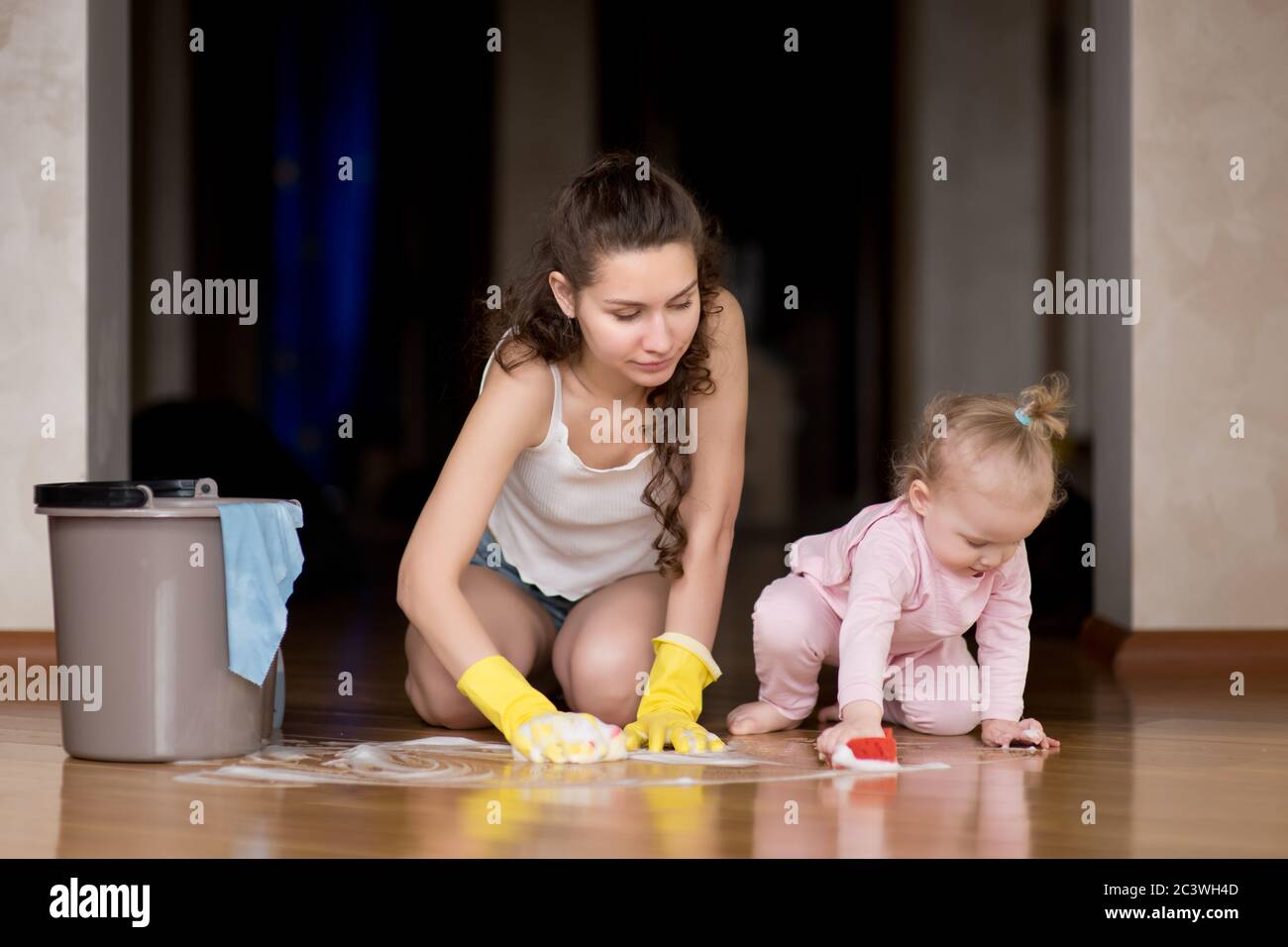 Mamma e figlia lavano il pavimento insieme a casa Foto Stock