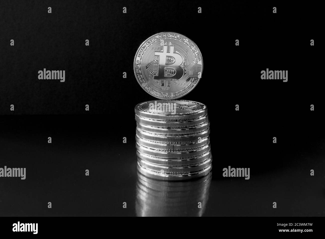 Su uno sfondo nero con spazio libero di testo sono monete d'argento di una criptovaluta digitale - Bitcoin. Oltre alle monete che giacciono, ci sono stand Foto Stock