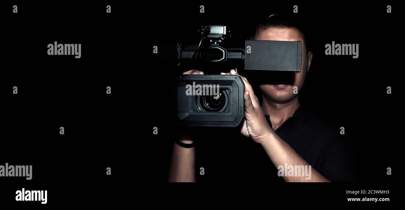 registrazione di filmati cameraman con fotocamera digitale per realizzare clip in produzione multimediale su sfondo scuro (dimensione banner) Foto Stock