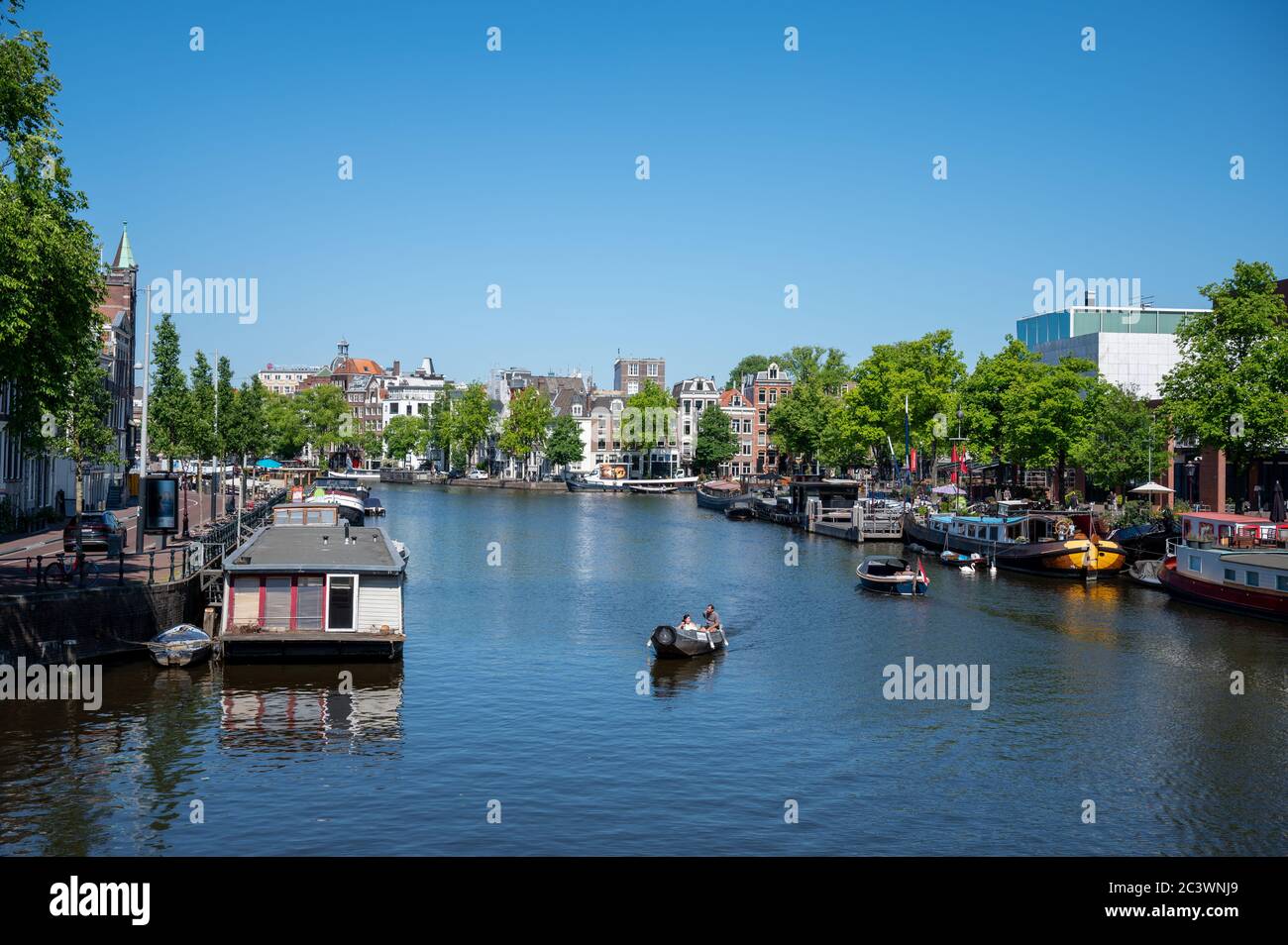 Barche sul fiume Amstel nel centro di Amsterdam, Paesi Bassi Estate ma non barche turistiche a causa del blocco di Coronavirus Foto Stock