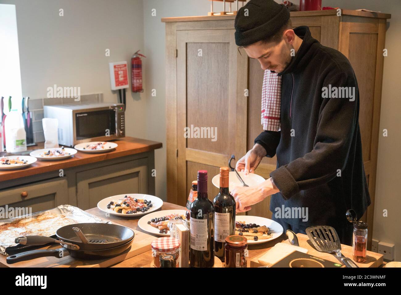 Un uomo che indossa un cappello da berretto prepara una colazione di 'toast  alla francese' con pancetta e mirtilli, Dorset, Inghilterra Foto stock -  Alamy