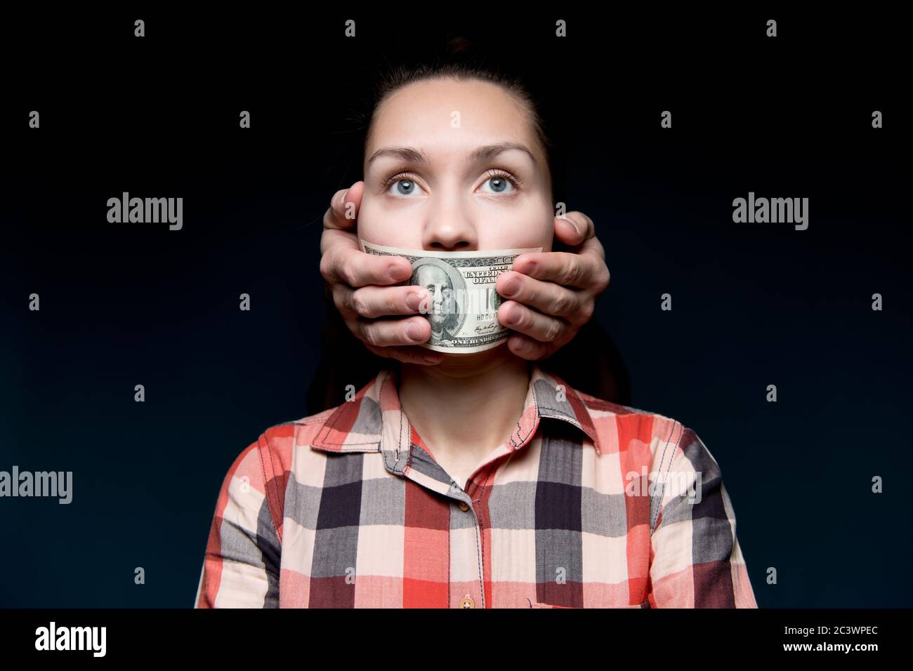 Le mani coprono la bocca di una donna con un conto di cento dollari. Acquisto silenzio Foto Stock