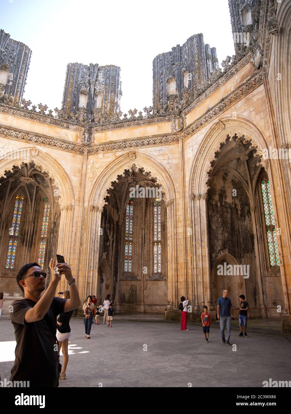 I turisti alla Cappella incompiuta con le sue colonne incompiuta e nessun tetto è stato commissionato dal re Duart al Monastero di Batalha Portogallo Foto Stock