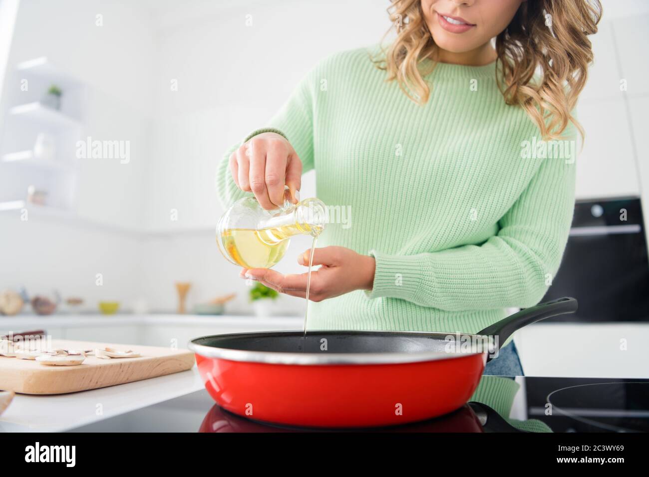 Foto ritagliata di bella casalinga tenere olio di oliva versando padella frittura calda gustare hobby mattina cucina gustosa cena stand famiglia luminosa cucina Foto Stock