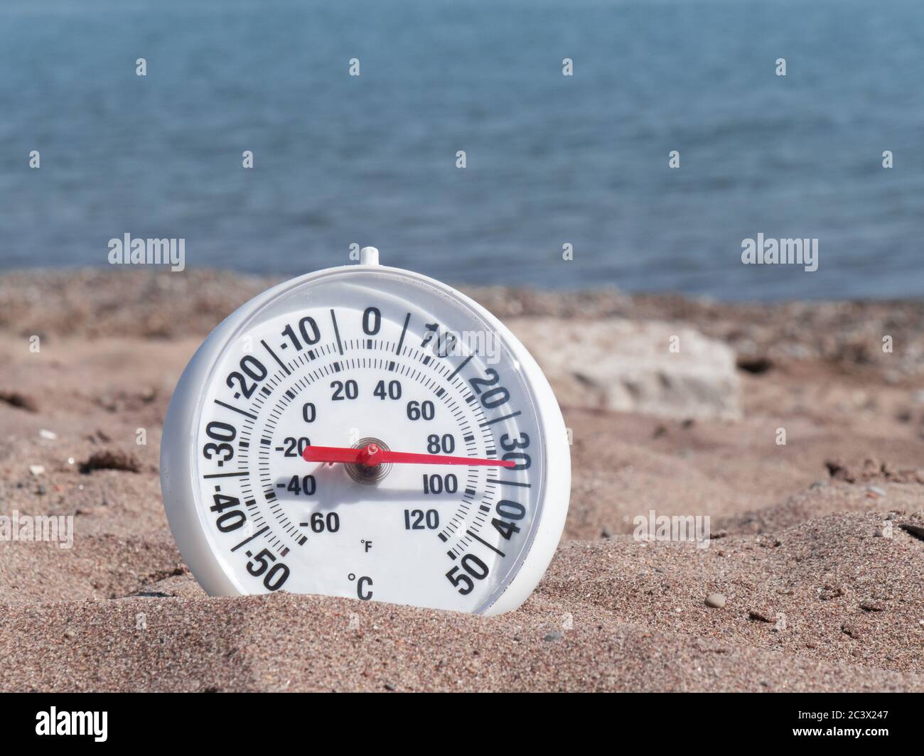 Un termometro rotondo sulla sabbia calda sulla spiaggia che mostra circa 90 gradi Fahrenheit 33 gradi Celsius Foto stock Alamy