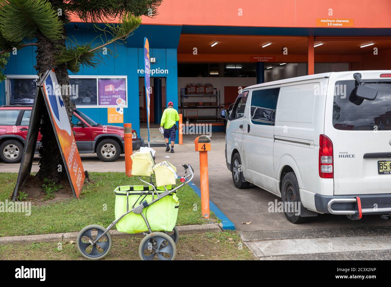 Il postino australiano con il carrello di consegna della posta consegna consegna la posta a a. Indirizzo aziendale a Sydney, Australia Foto Stock