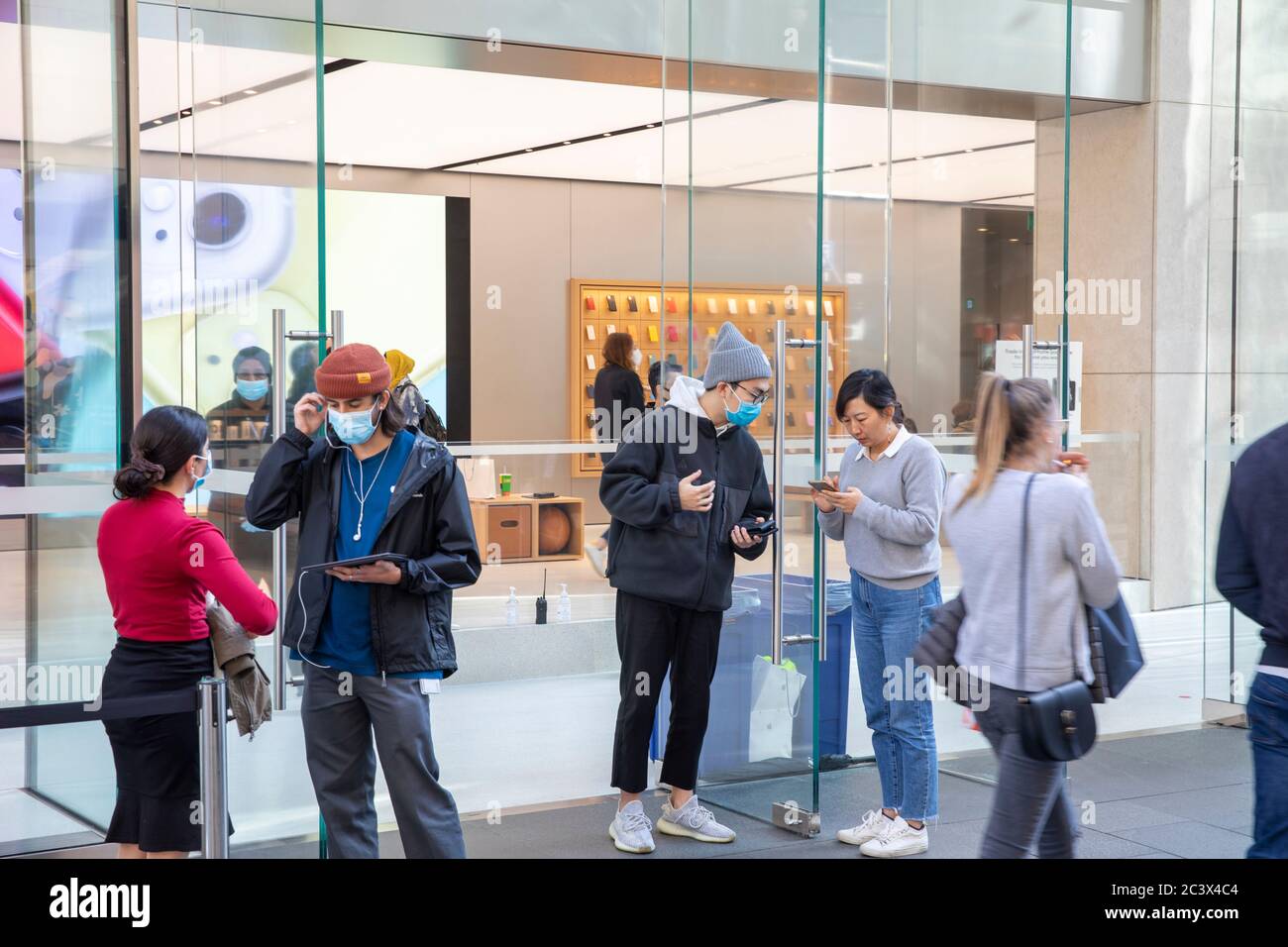 Covid 19 e il negozio di punta Apple a Sydney, il personale addetto alla sicurezza controlla la temperatura e la salute dei clienti che consegnano le maschere per entrare nel negozio Foto Stock