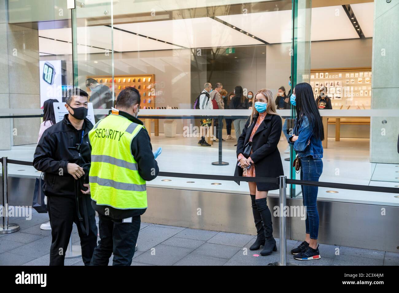 Covid 19 e il negozio di punta Apple a Sydney, il personale addetto alla sicurezza controlla la temperatura e la salute dei clienti che consegnano le maschere per entrare nel negozio Foto Stock