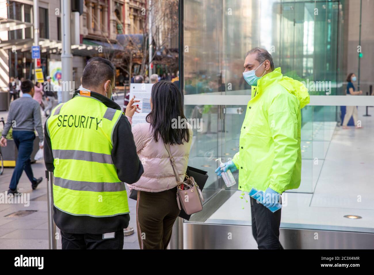 Covid 19 e il negozio di punta Apple a Sydney, il personale addetto alla sicurezza controlla la temperatura e la salute dei clienti che consegnano le maschere per entrare nel negozio Foto Stock