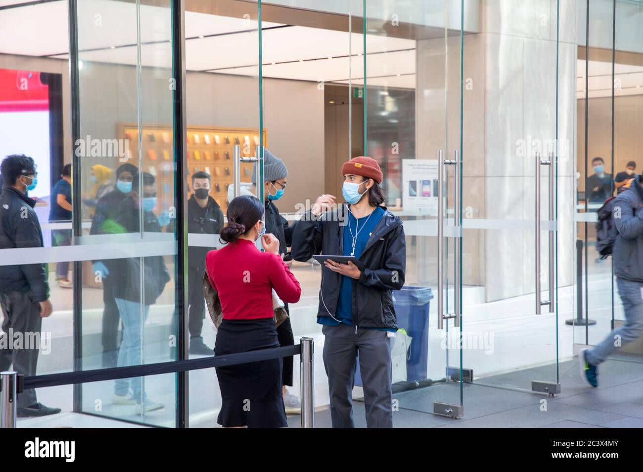 Covid 19 e il negozio di punta Apple a Sydney, il personale addetto alla sicurezza controlla la temperatura e la salute dei clienti che consegnano le maschere per entrare nel negozio Foto Stock