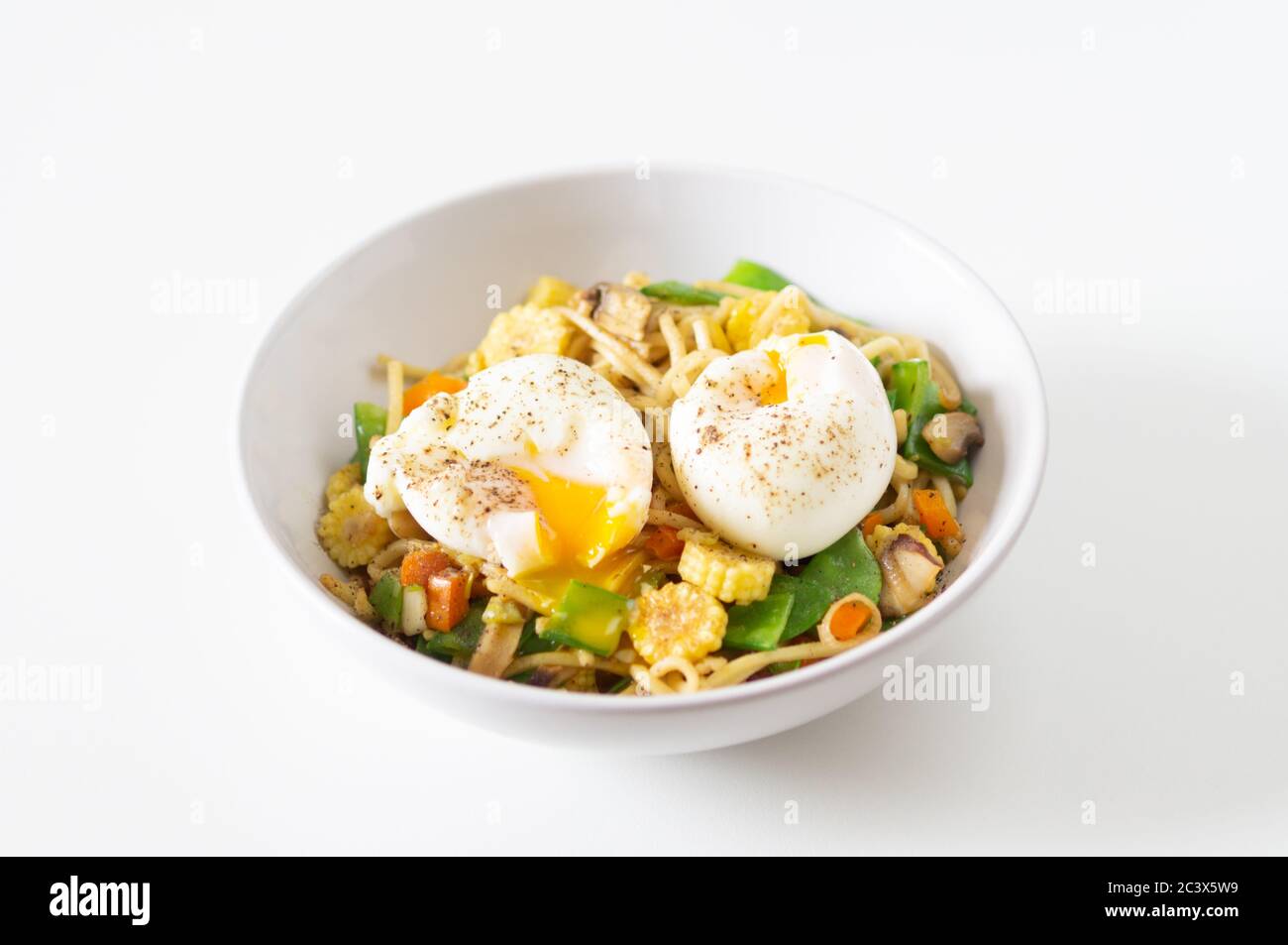 Mescolare la friggitrice con tagliatelle, mais, tout di mange, funghi, cipolla e pepe con uova sode morbide - vegetariane, senza carne, sane, proteiche Foto Stock