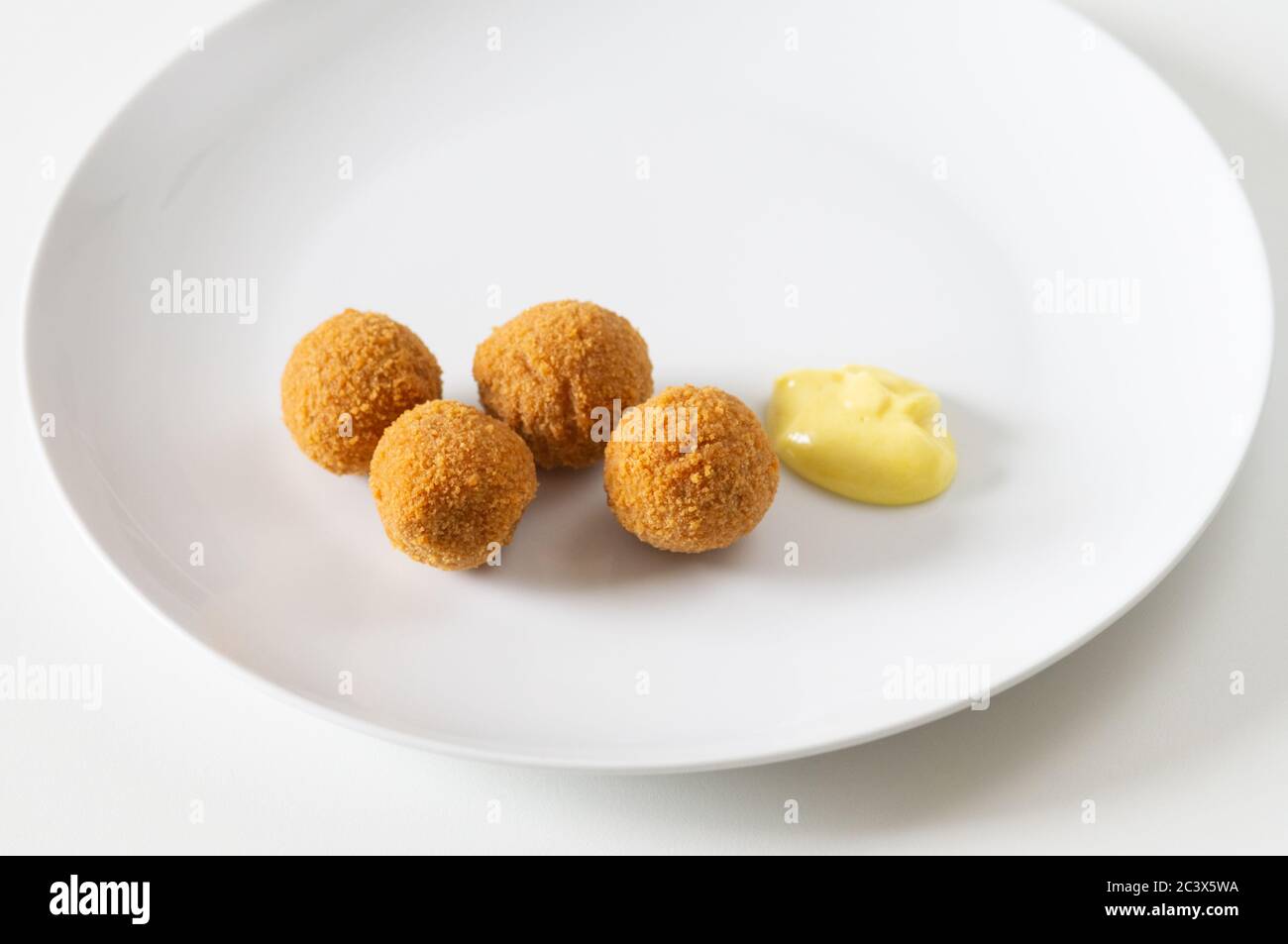 Uova di scotch vegetariane/senza carne o uova da picnic con una salsa di senape delicata su un piatto bianco - snack, cibo, senza carne, quorn, micoproteina Foto Stock