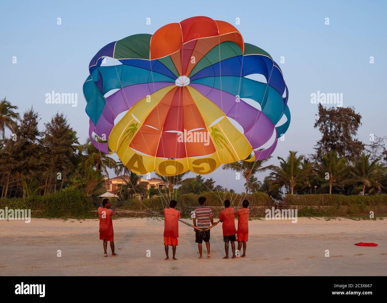 Uomini sulla spiaggia che abbattere un parasailing alla fine della giornata a Goa, India. Foto Stock