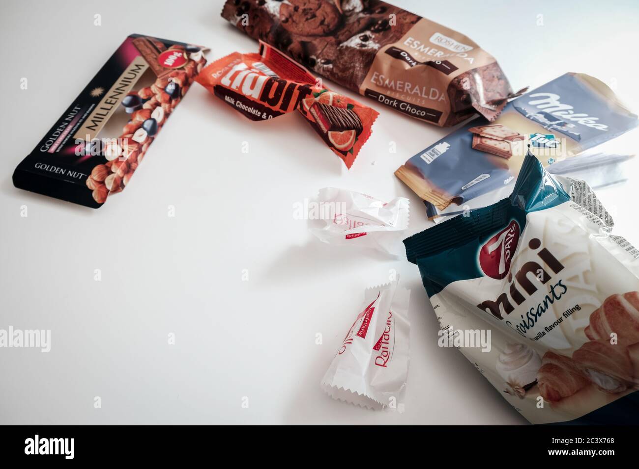 Lviv / Ucraina - Aprile 2020: Caramelle assortite, biscotti e involucri di cioccolato lasciati su un tavolo bianco. Deliziosi dolci pieni di zucchero Foto Stock