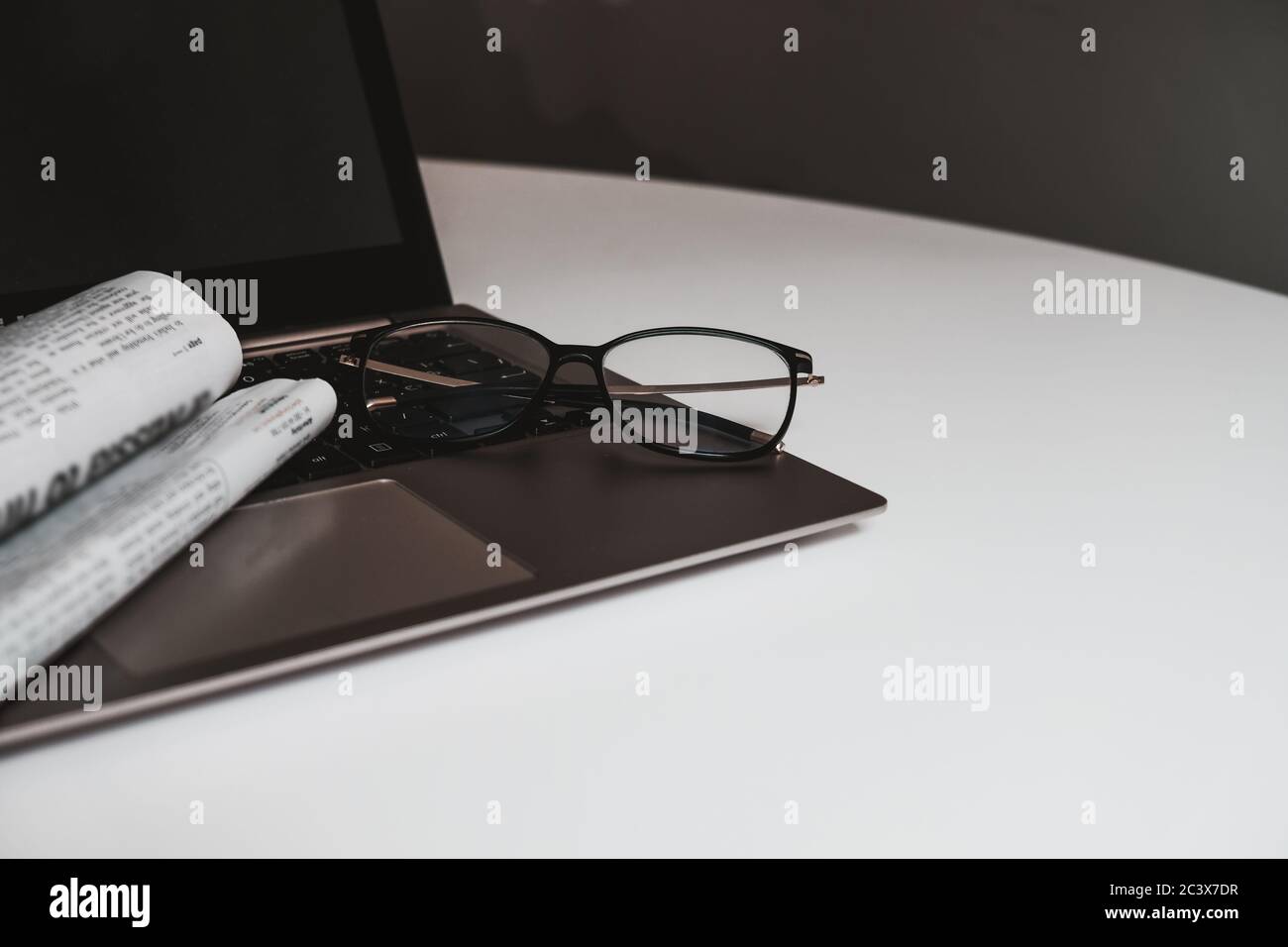 Spazio di lavoro per l'ufficio domestico per l'isolamento. Luogo di apprendimento per la casa o il luogo di lavoro per un freelance. Scrivania bianca con spazio vuoto. Giornale, bicchieri. Foto Stock