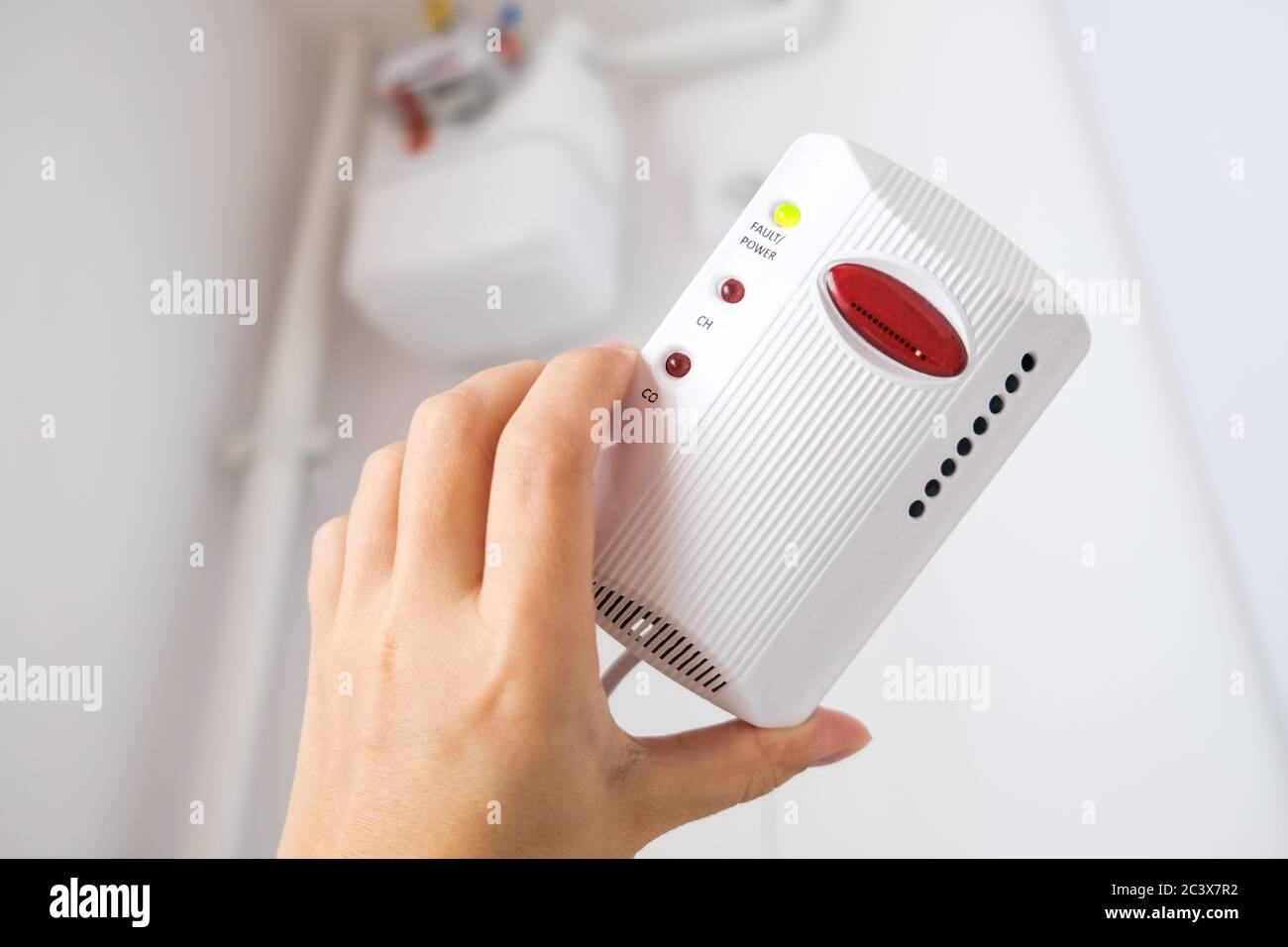 Tipico sensore di gas in Europa. Dispositivo rilevatore di gas bianco in mano per prevenire perdite di gas e garantire la sicurezza a casa. Allarme di rilevamento del fumo in Europa Foto Stock