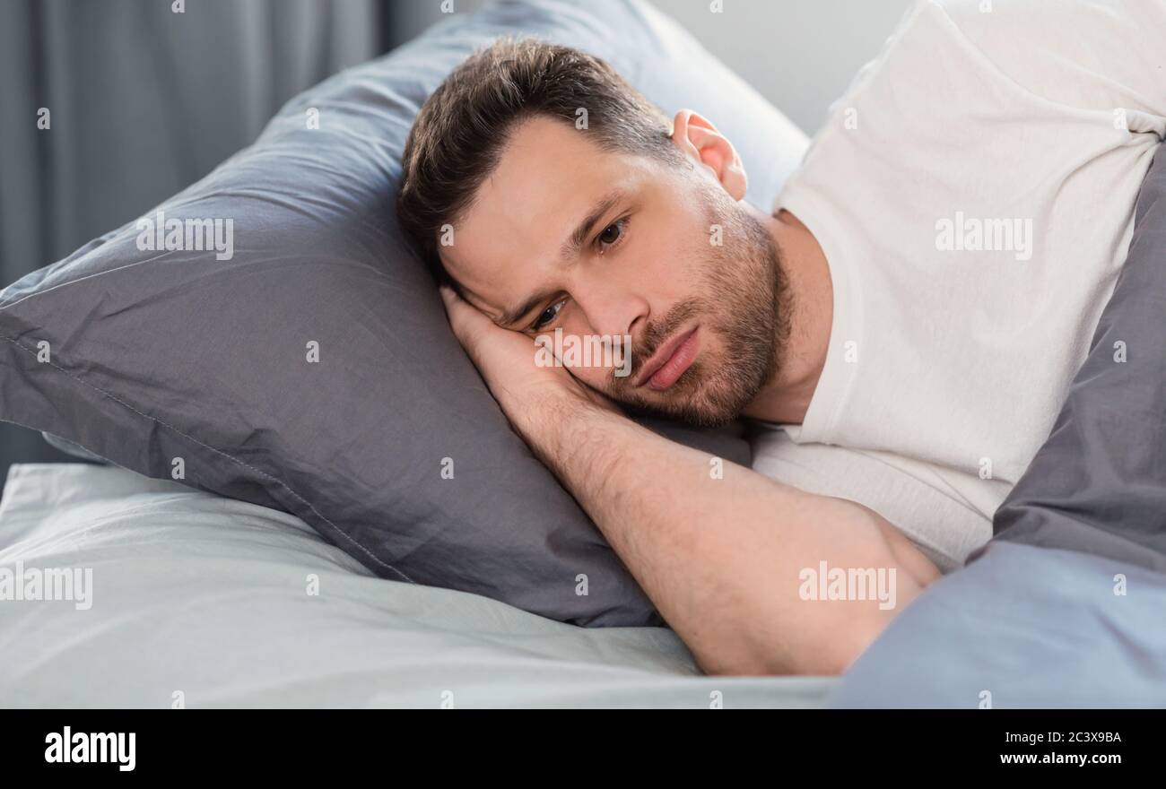 Uomo depresso che ha Insomnia che si trova a letto a casa Foto Stock