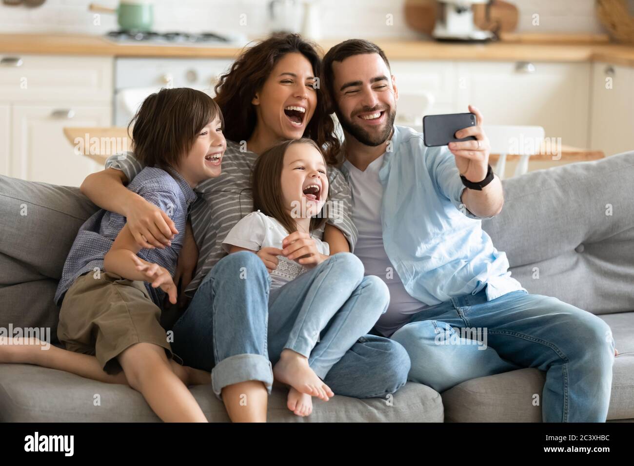 Primo piano genitori felici con bambini piccoli che usano lo smartphone insieme. Foto Stock