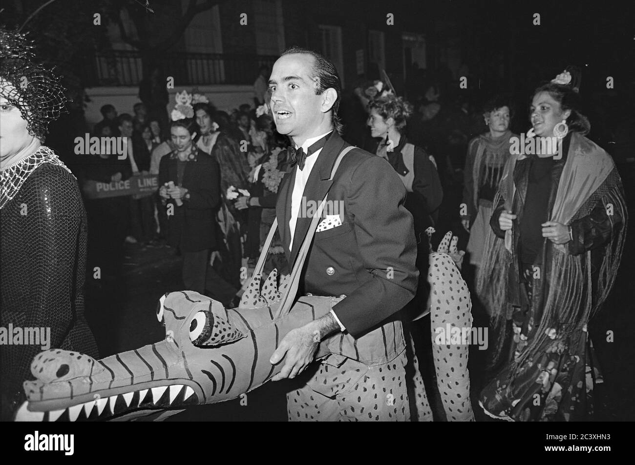 Uomo in tux e alligatore alla Greenwich Village Halloween Parade, New York City, USA negli anni '80 fotografato con film in bianco e nero di notte. Foto Stock