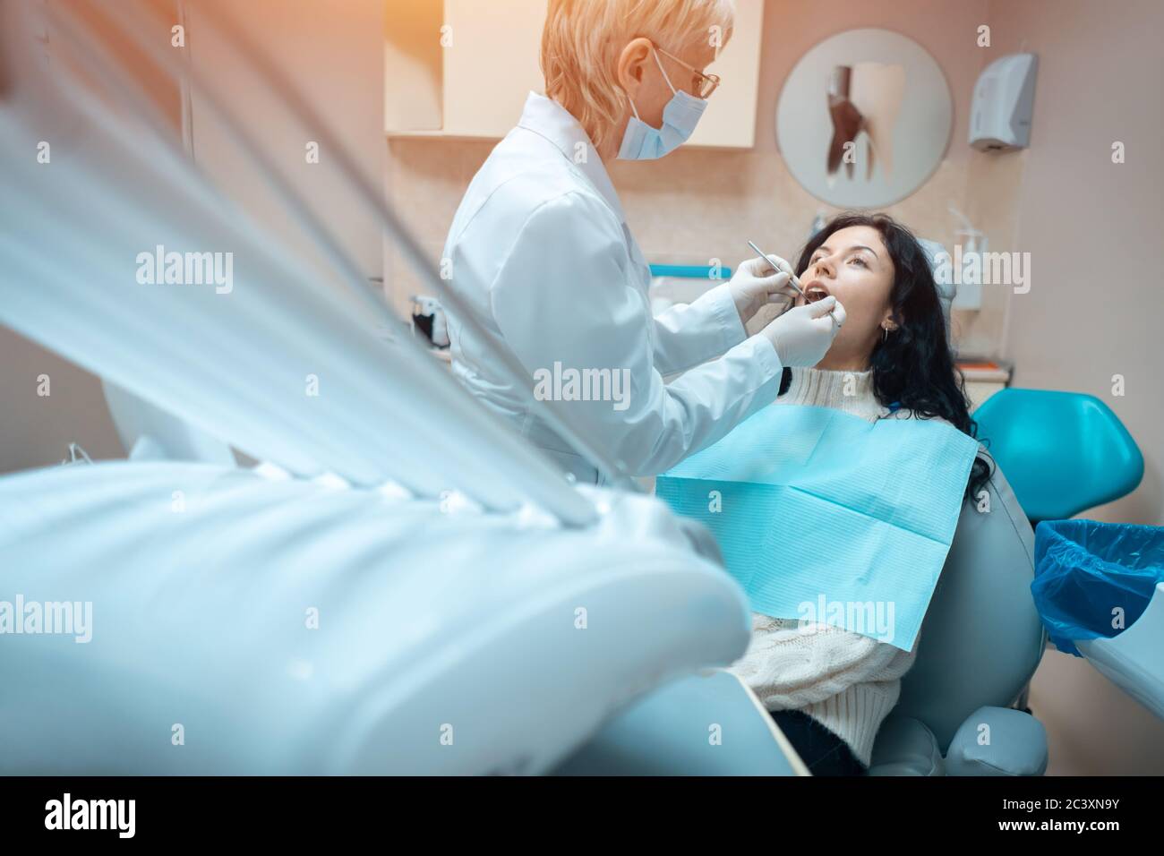 bella brunette curly donna dentista trattare paziente in clinica moderna Foto Stock