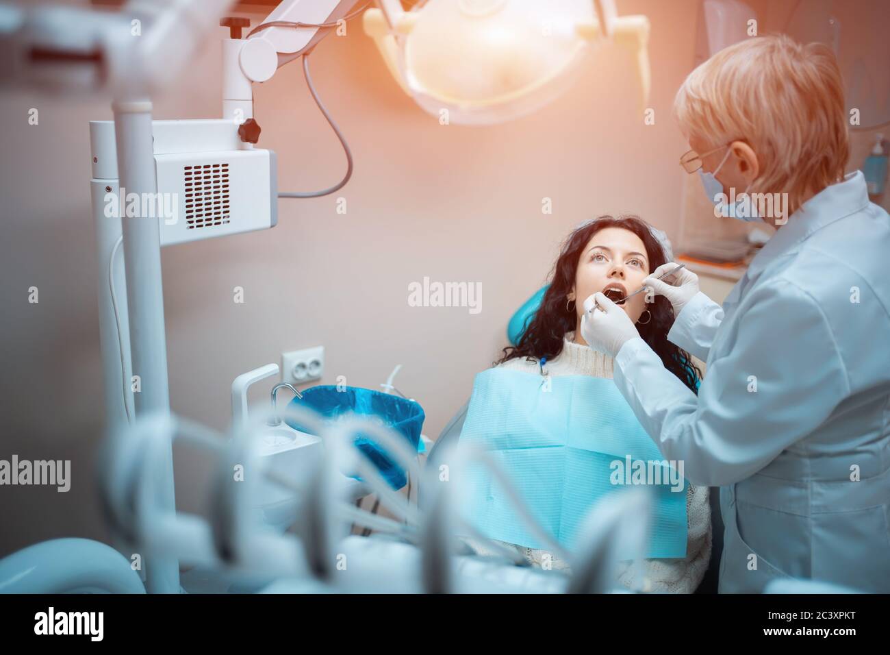 bella brunette curly donna dentista trattare paziente in clinica moderna Foto Stock