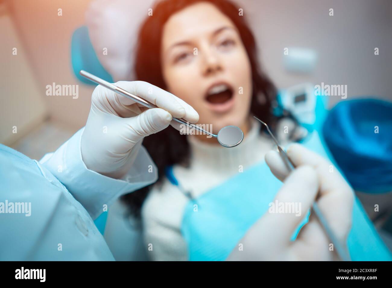 bella brunette curly donna dentista trattare paziente in clinica moderna Foto Stock