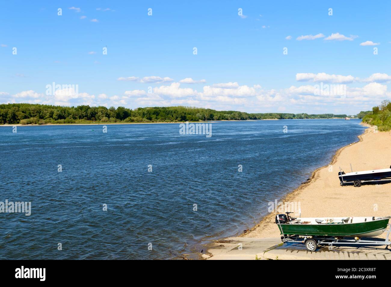 Incredibile fiume blu increspato con spiaggia sabbiosa, alberi verdi e barche Foto Stock