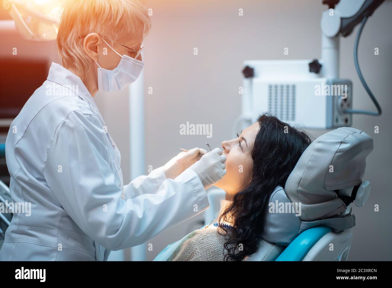 bella brunette curly donna dentista trattare paziente in clinica moderna Foto Stock