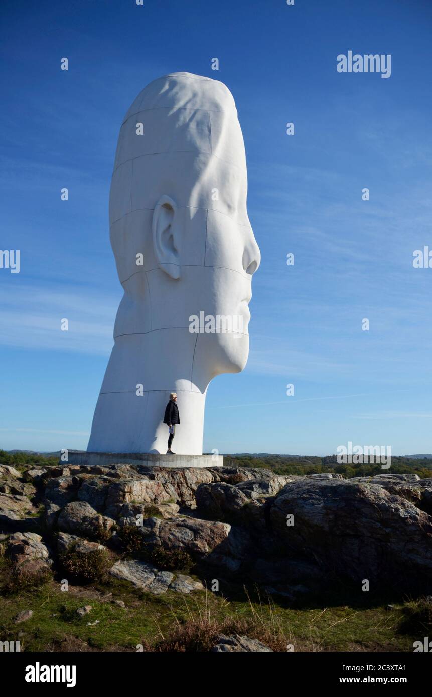 Una donna si trova accanto a una scultura oversize di Jaume Plensa, al PILANE SKULPTURE PARK, Tjörn, Svezia. Foto Stock