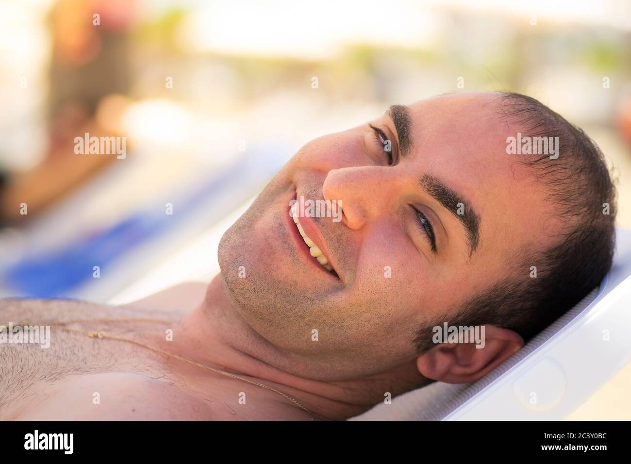 Uomo mediterraneo che si rilassa su un lettino sulla spiaggia. Foto Stock