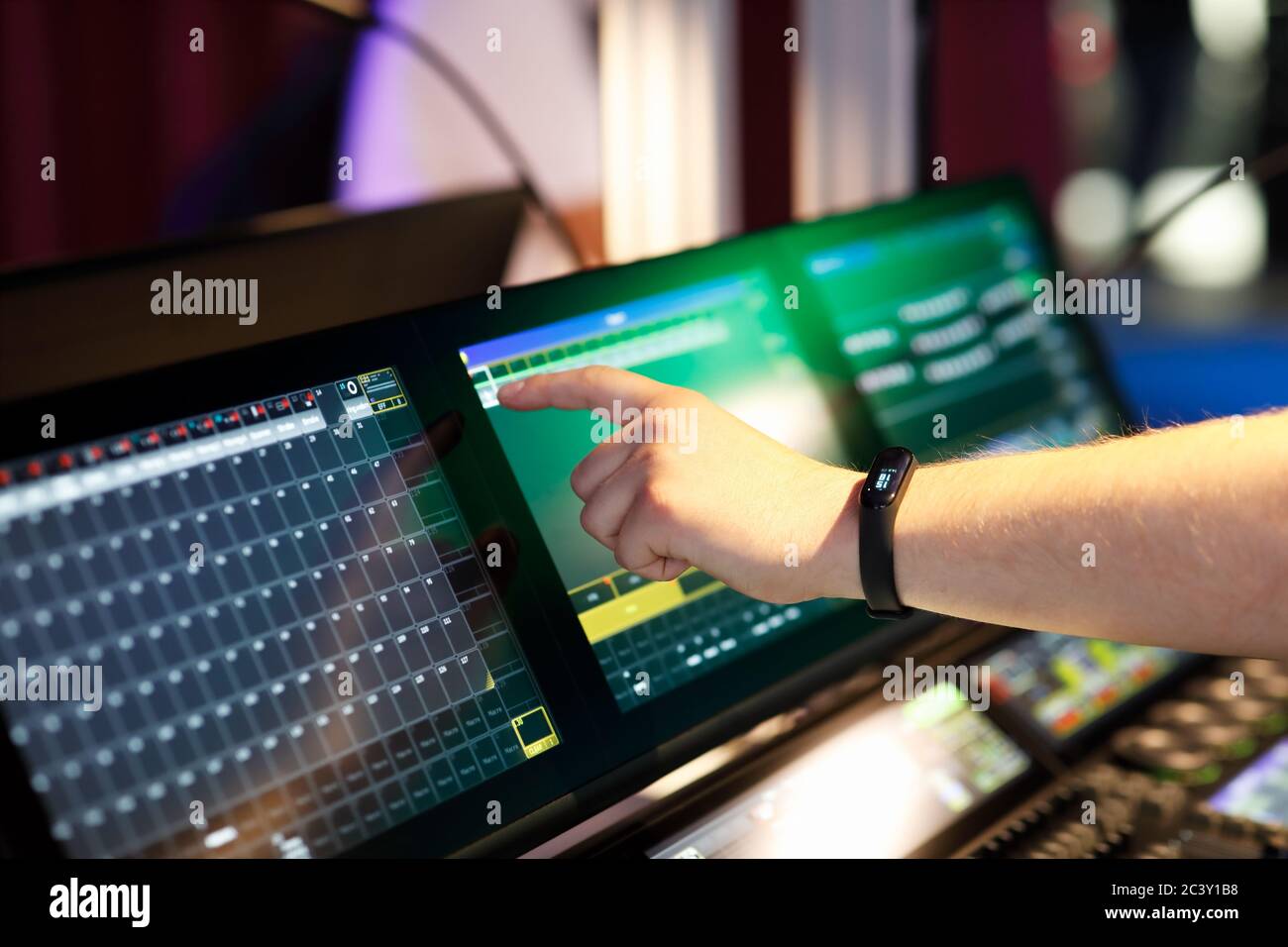 Progettista di illuminazione che lavora con la console di controllo dell'illuminazione della scena utilizzando il touchscreen. Messa a fuoco selettiva. Foto Stock