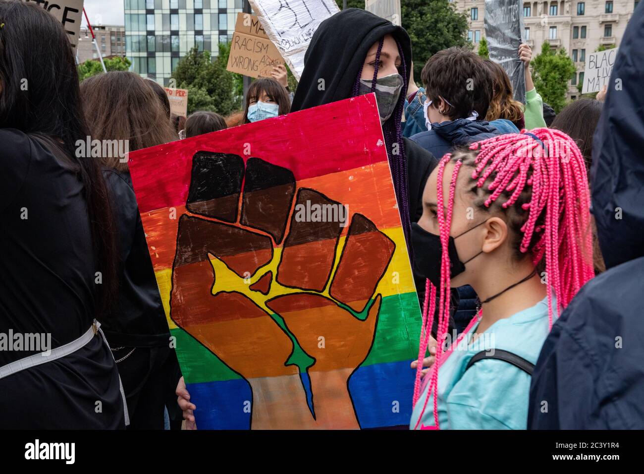 Giovane protestore che tiene un bordo 'Black Lives Matter, un pugno nero e colori arcobaleno'' durante l'assemblea di protesta in solidarietà al movimento BLM Foto Stock