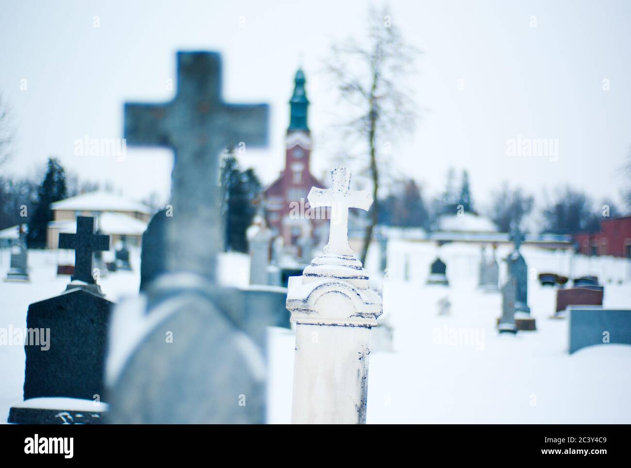 Hampton, Minnesota, Stati Uniti, 30 dicembre 2009. Una croce sulla cima di una lapide di fronte ad una chiesa tradizionale. Foto Stock