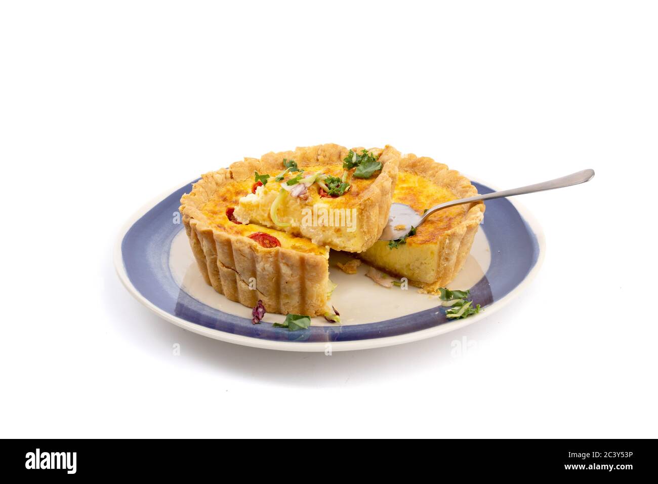 una quiche di formaggio con pomodori secchi con un pezzo tagliato pronto per servire isolato su bianco Foto Stock