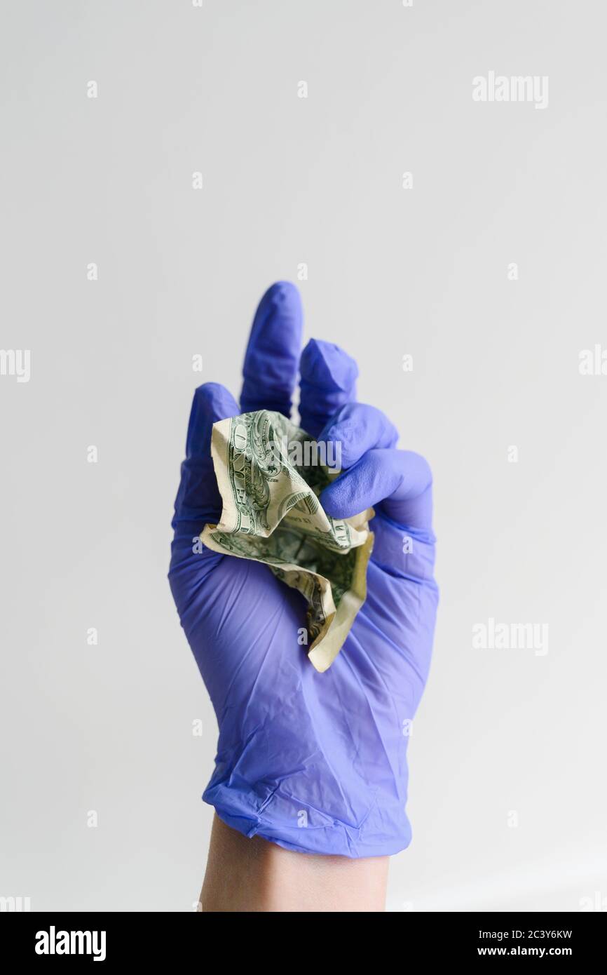 Studio shot di mano in guanto di lattice che tiene il dollaro crumpled fattura Foto Stock