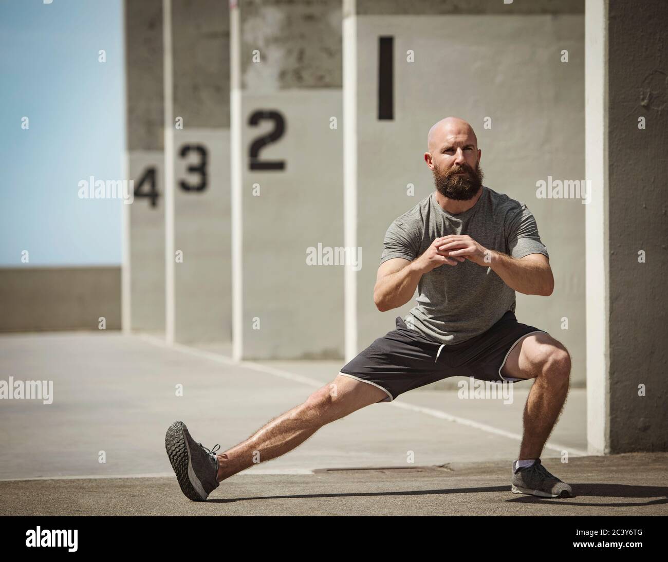 Uomo che si allunga durante l'allenamento Foto Stock