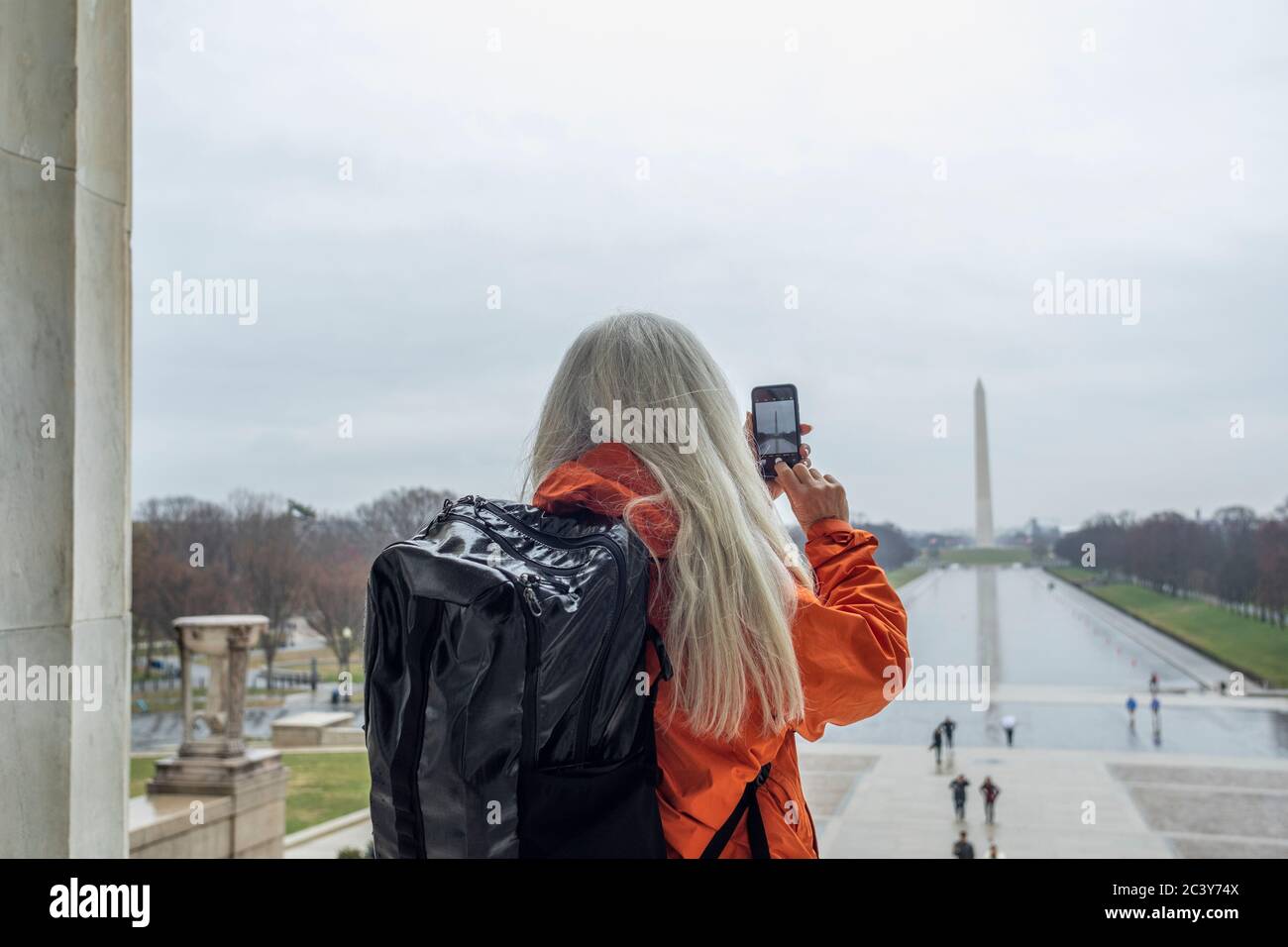 USA, Washington D.C., Tourist scatta foto del monumento di Washington attraverso lo stagno al National Mall utilizzando uno smartphone Foto Stock