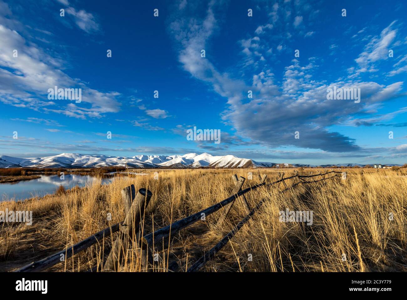 USA, Idaho, Sun Valley, Paesaggio con recinzione, erba e montagna innevata sullo sfondo Foto Stock