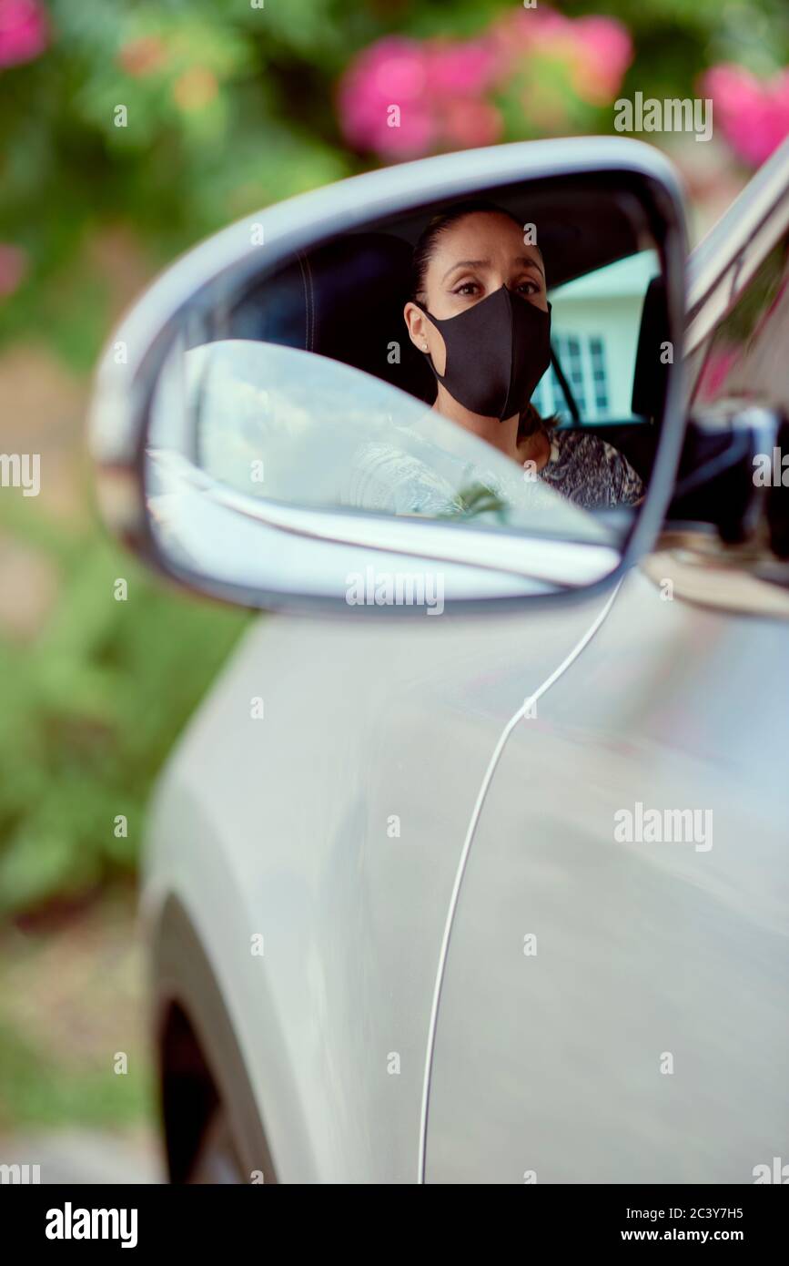 Donna con maschera di guida auto riflessa nello specchio Foto Stock